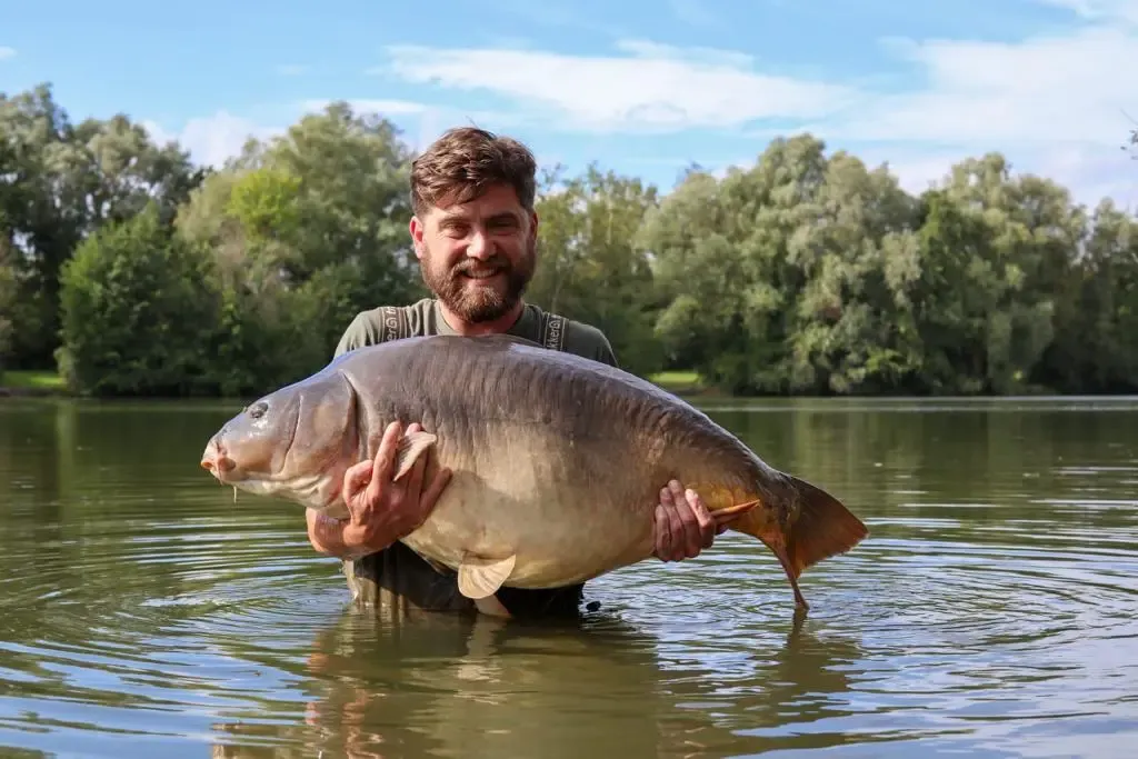 Homme barbu tenant un gros poisson dans ses mains